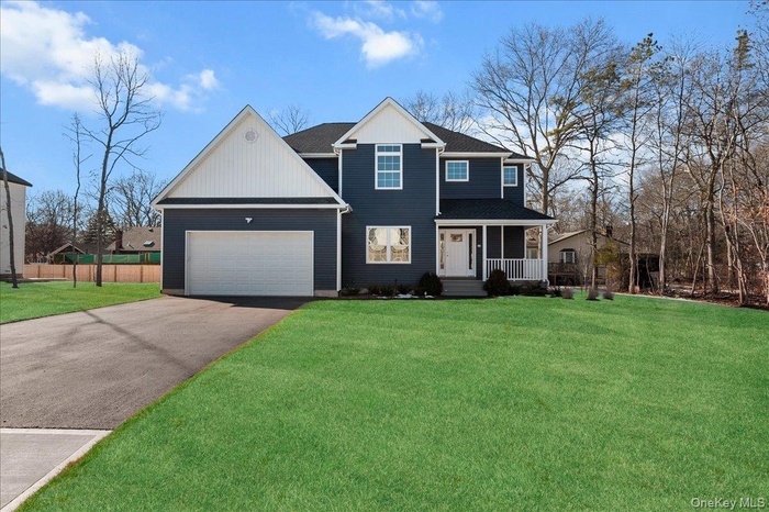 Traditional-style house featuring a porch, an attached garage, asphalt driveway, and roof with shingles