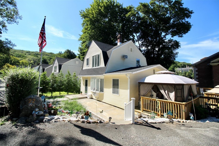View of front of home with a gazebo, roof with shingles, a gambrel roof, and a patio area