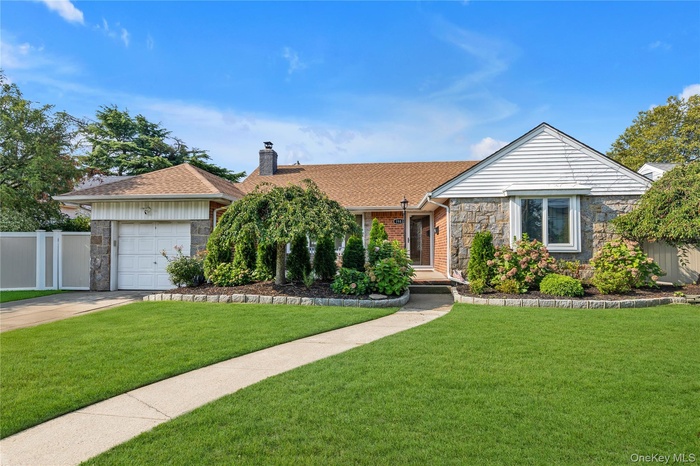 Ranch-style house featuring stone siding, a chimney, a garage, driveway, and roof with shingles