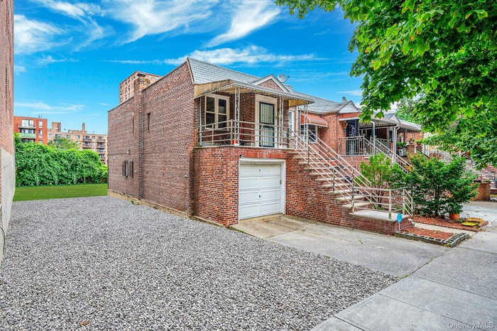 View of front of home featuring brick siding, stairs, driveway, an attached garage, and covered porch