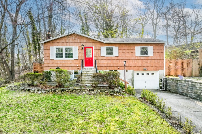 View of front of home featuring an attached garage, a front lawn, aphalt driveway, entry steps, and a chimney