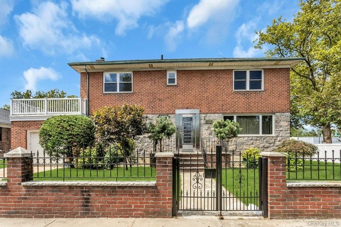View of front of house featuring a fenced front yard, a gate, stone siding, and brick siding