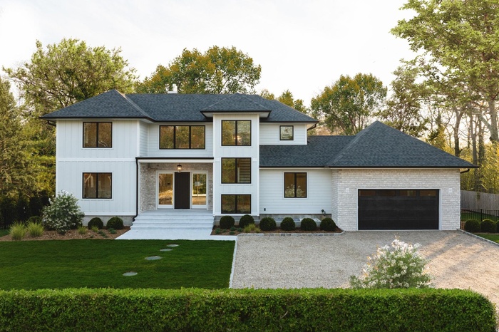 View of front of home featuring driveway, an attached garage, roof with shingles, and a front yard