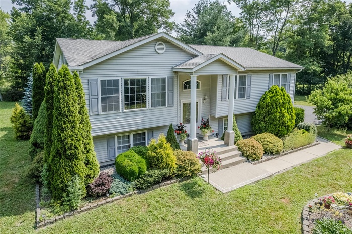 Split foyer home with a shingled roof and a front yard
