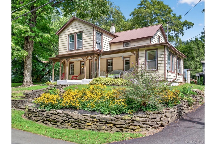 View of front facade featuring covered porch and a chimney