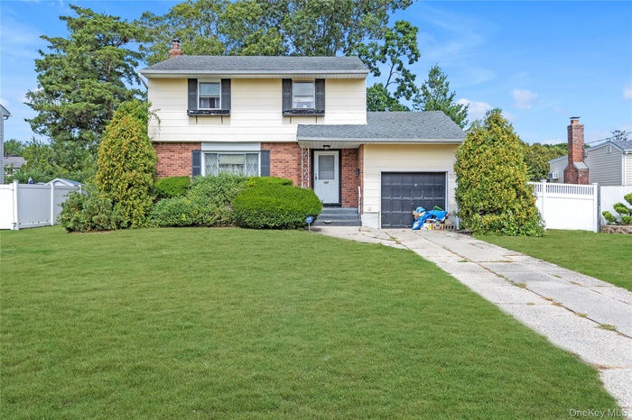 View of front of home featuring brick siding, an attached garage, concrete driveway, a chimney, and roof with shingles