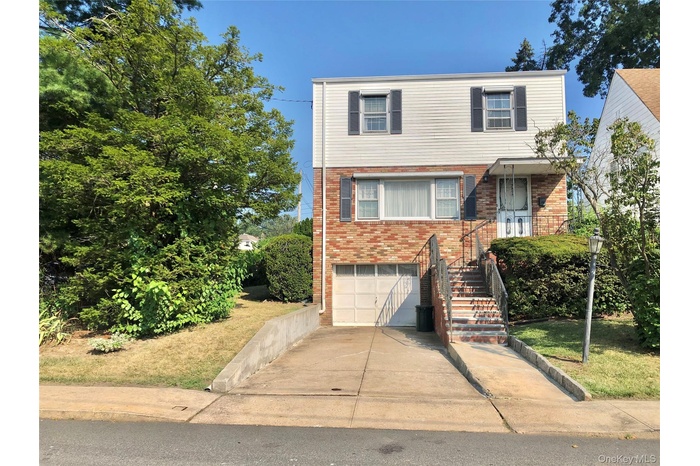 View of front of property featuring brick siding, concrete driveway, and an attached garage