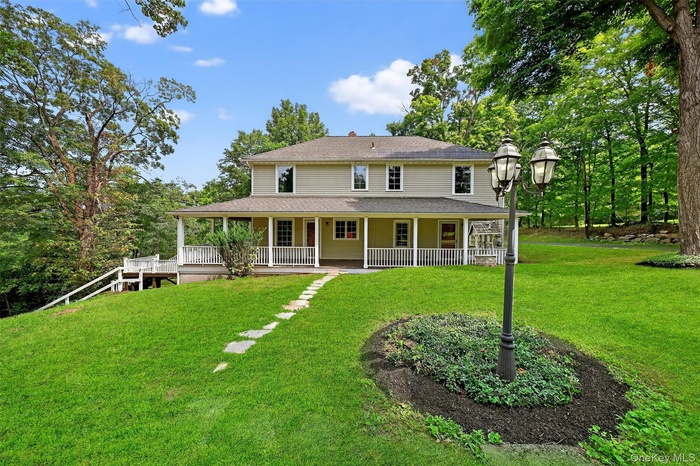 Rear view of property with a large porch, a yard, and a shingled roof