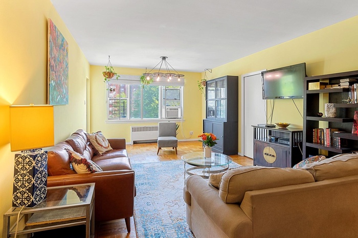 Living area featuring baseboards, cooling unit, and radiator heating unit