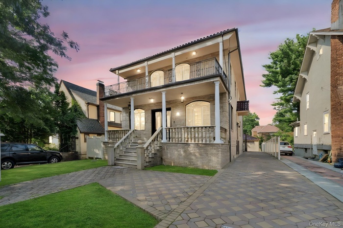 View of front of house featuring covered porch, brick siding, a balcony, and a gate