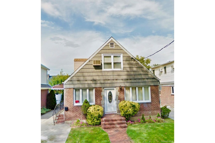 Bungalow-style home with brick siding, a front lawn, and a wall mounted AC