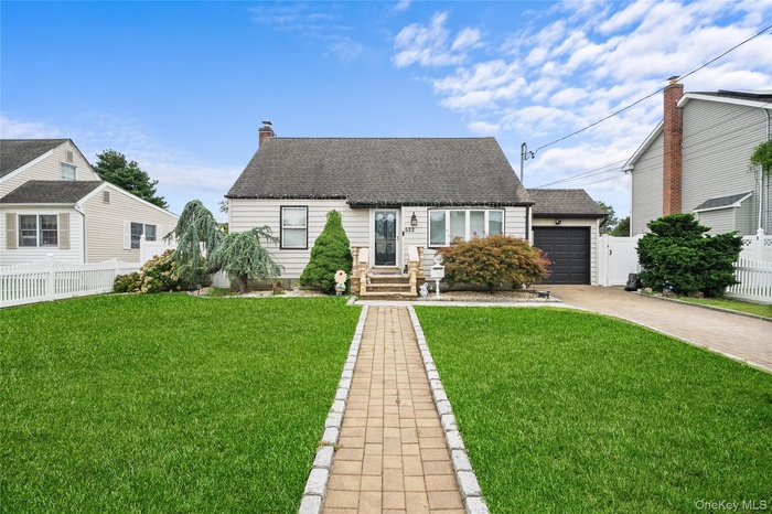 View of front of home with driveway, roof with shingles, a garage, and a chimney