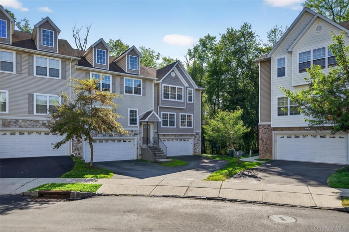 View of front facade with asphalt driveway, an attached garage, and stone siding