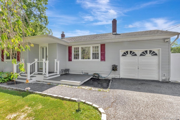 View of front of property with an attached garage, a deck, roof with shingles, and a chimney
