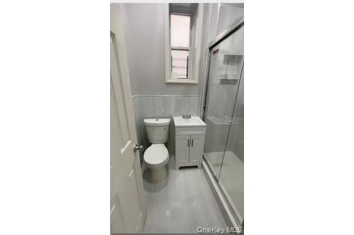 Bathroom featuring vanity, a stall shower, and a wainscoted wall