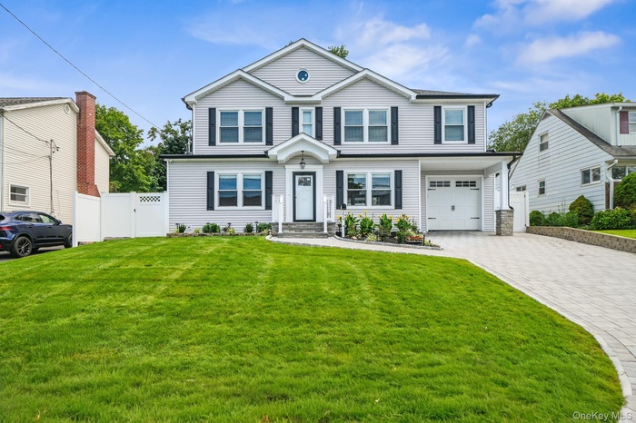 View of front of house featuring decorative driveway, an attached garage, and a gate