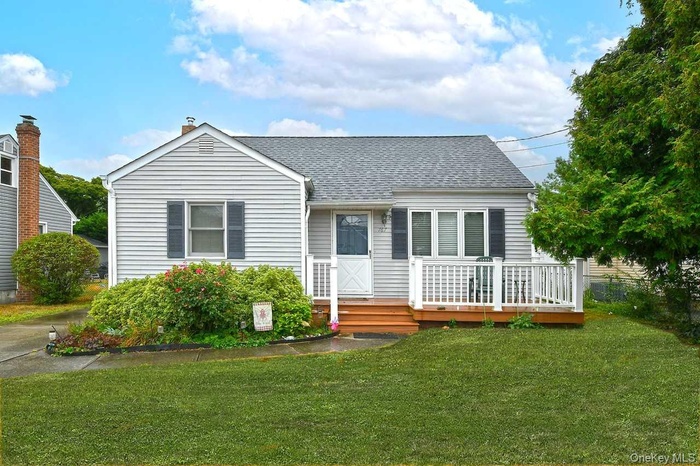 View of front of home with a wooden deck, a front yard, and a shingled roof