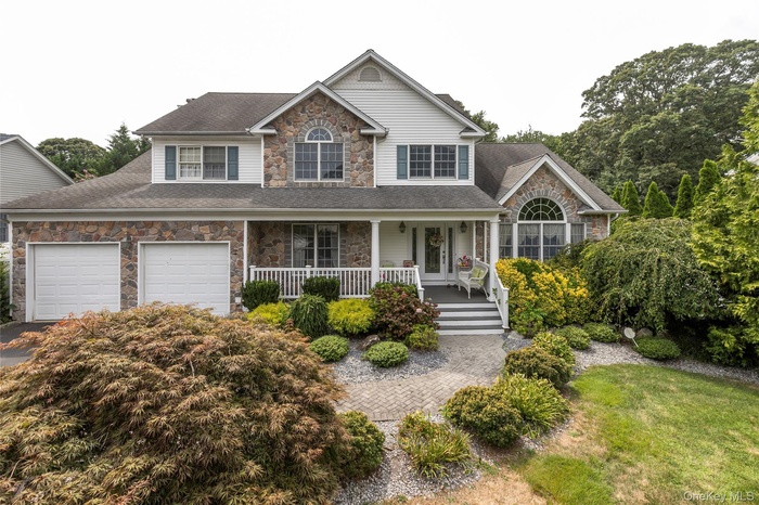 Traditional-style home featuring stone siding, a porch, and roof with shingles