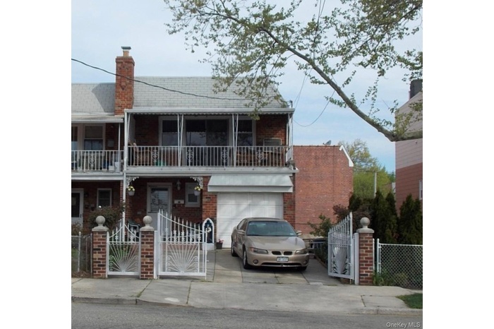 View of front facade with a gate, driveway, a fenced front yard, brick siding, and a garage