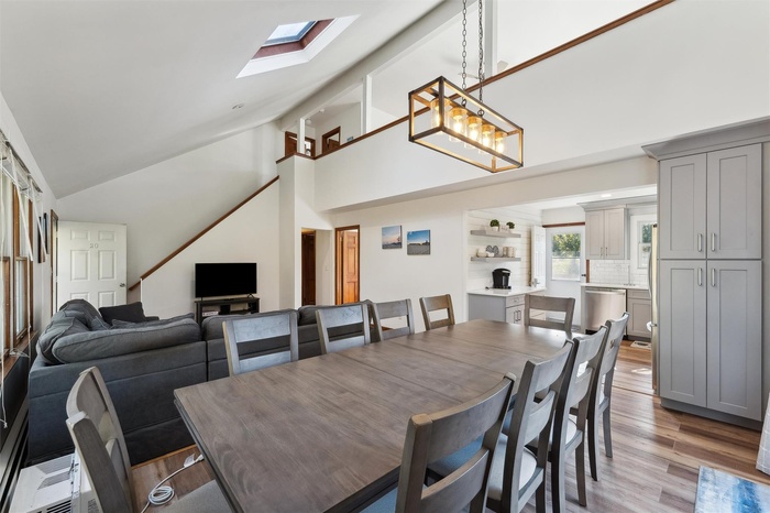 Open Dining/Living  room with light wood-style floors, a skylight, and high  ceiling.