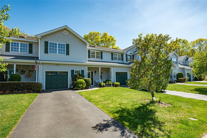 View of front of house featuring an attached garage, driveway, a front yard, and a shingled roof