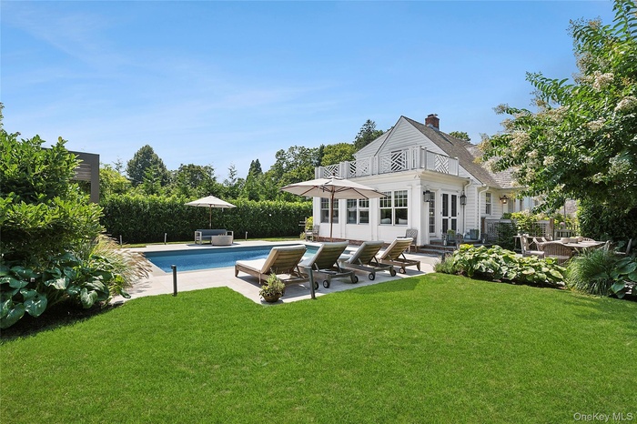 Back of property with a patio area, a yard, a chimney, and a balcony