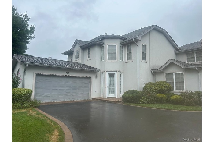 Traditional-style home with asphalt driveway, a garage, and stucco siding