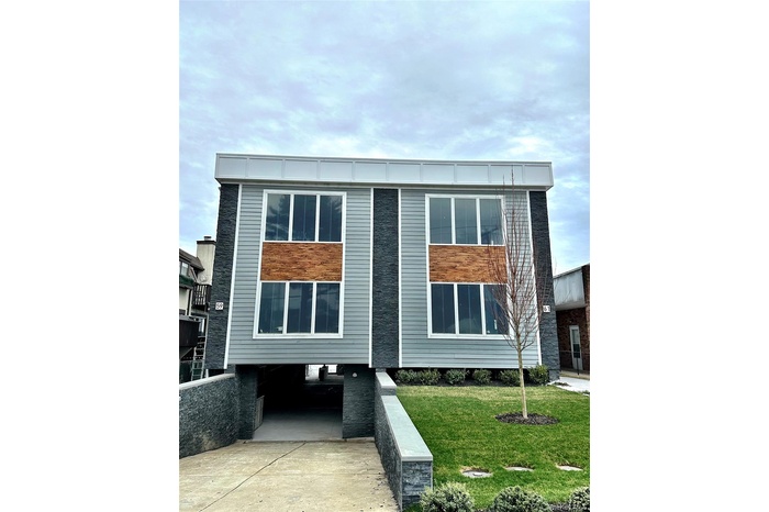 Modern home featuring a front yard, an attached garage, and driveway