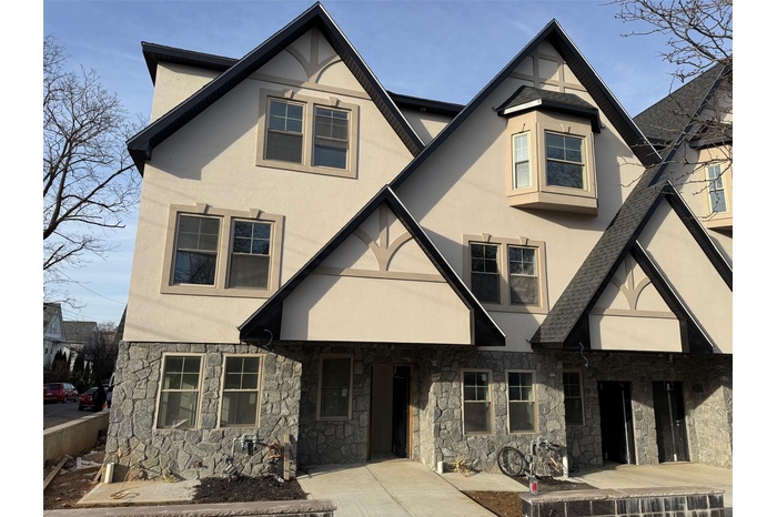 View of front of home featuring stone siding, roof with shingles, and stucco siding