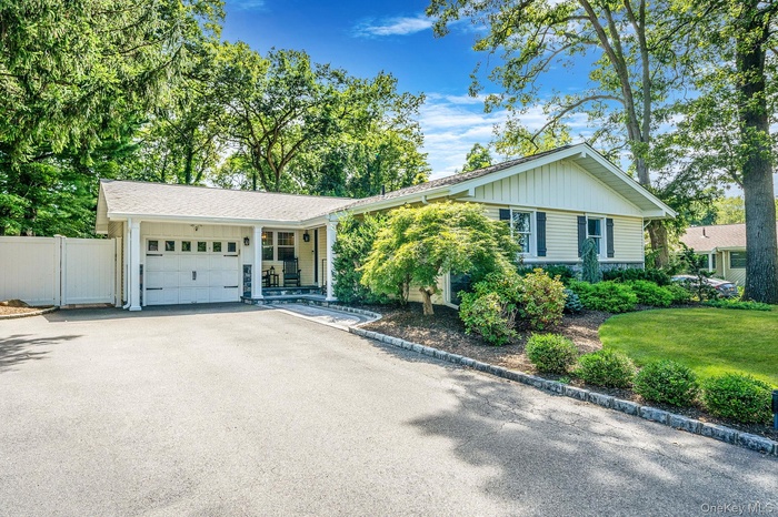 View of front of house featuring a garage, board and batten siding, asphalt driveway, and a porch