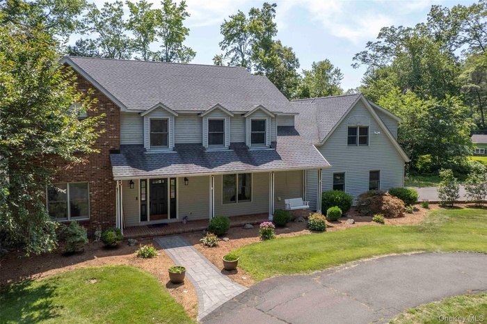 View of front of home with a porch, a front lawn, and a shingled roof