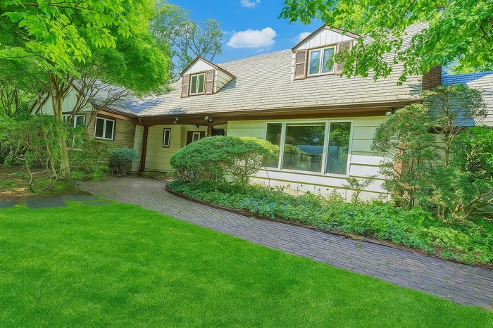 Cape cod home featuring a front lawn and a chimney