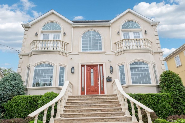 View of front of home with stucco siding and a balcony