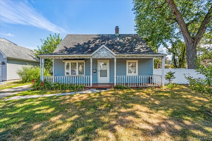 Bungalow-style house with covered porch, a chimney, a front yard, and roof with shingles