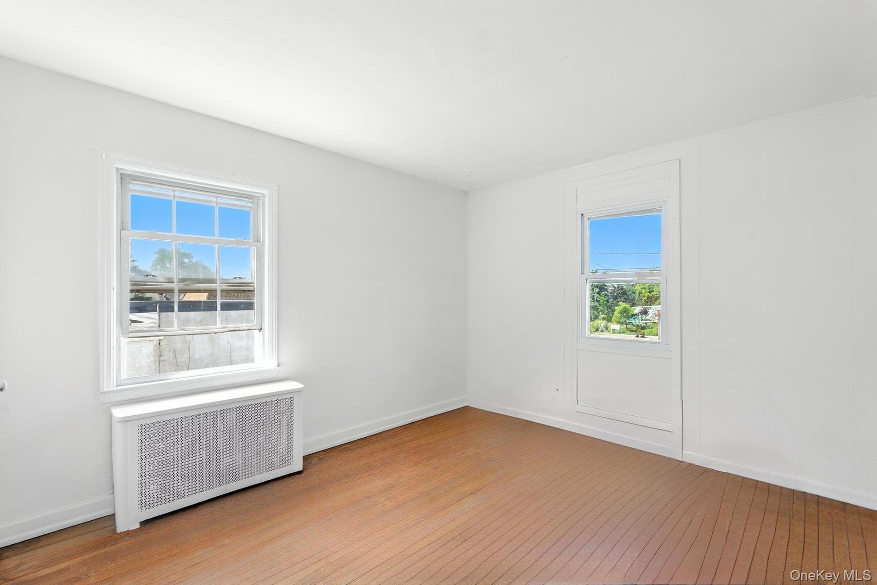 Spare room with radiator heating unit and light wood-type flooring