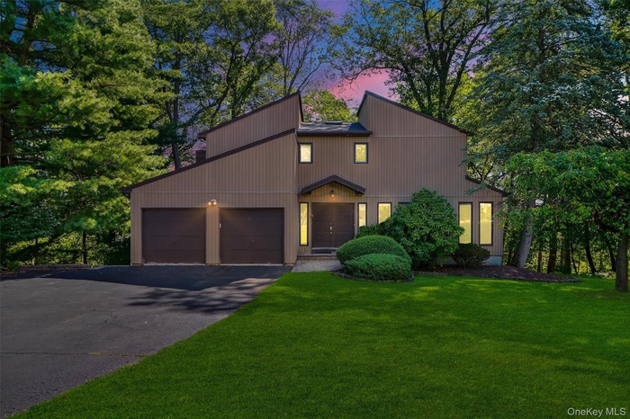 View of front of property featuring driveway, an attached garage, and a front lawn