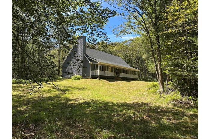 View of front of home featuring a porch, a front yard, and a chimney