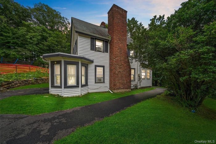 View of front facade featuring a front lawn and a chimney