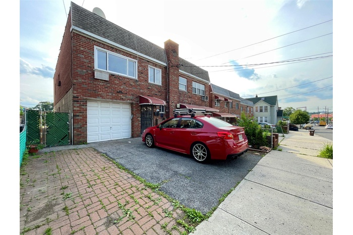 View of front facade with roof with shingles, asphalt driveway, a garage, brick siding, and mansard roof