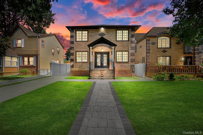 View of front of property featuring brick siding, concrete driveway, and french doors
