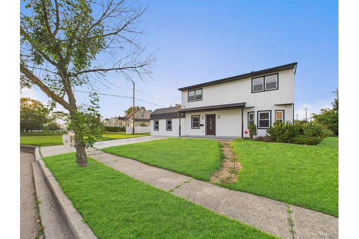 View of front of property with a front lawn and concrete driveway