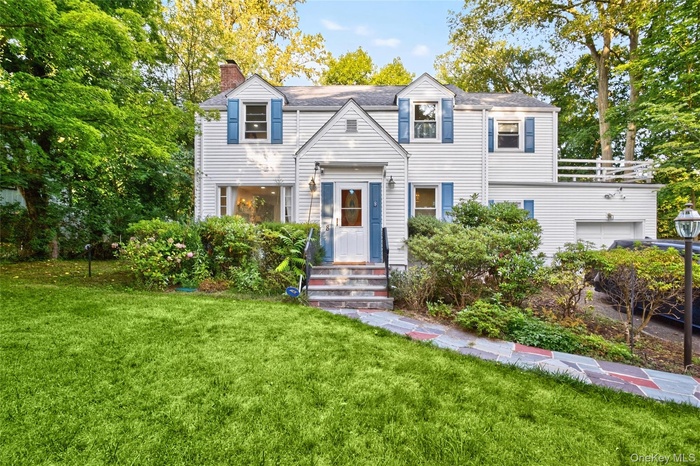 View of front of property featuring a chimney, a front lawn, and an attached garage