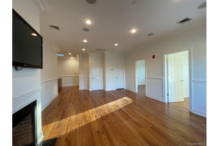 Unfurnished living room featuring crown molding, dark wood-type flooring, recessed lighting, and a fireplace