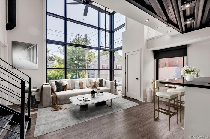 Living area with a high ceiling, stairs, dark wood finished floors, expansive windows, and recessed lighting