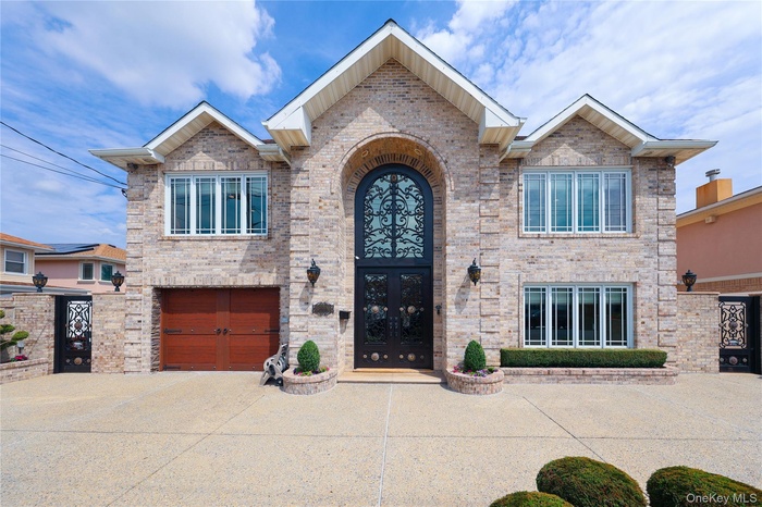 View of front of property featuring an attached garage, concrete driveway, and brick siding