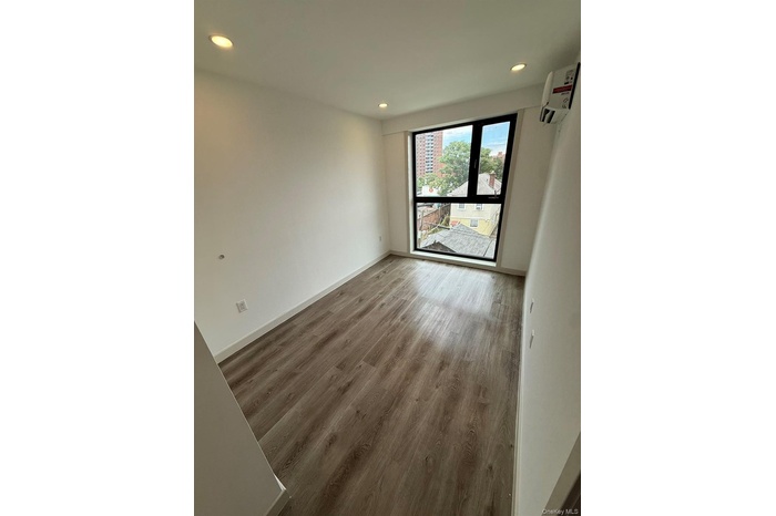 Spare room featuring recessed lighting, wood finished floors, and an AC wall unit