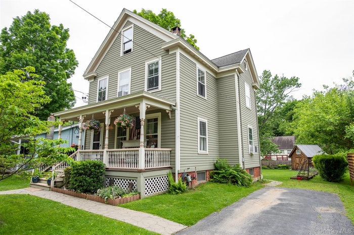 View of front of home with covered porch, a front lawn, and a chimney