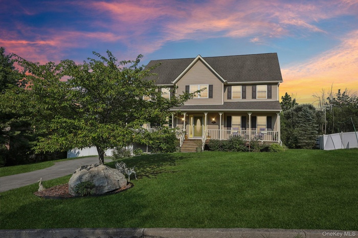 View of front of house featuring covered porch, a front yard, driveway, and a shingled roof