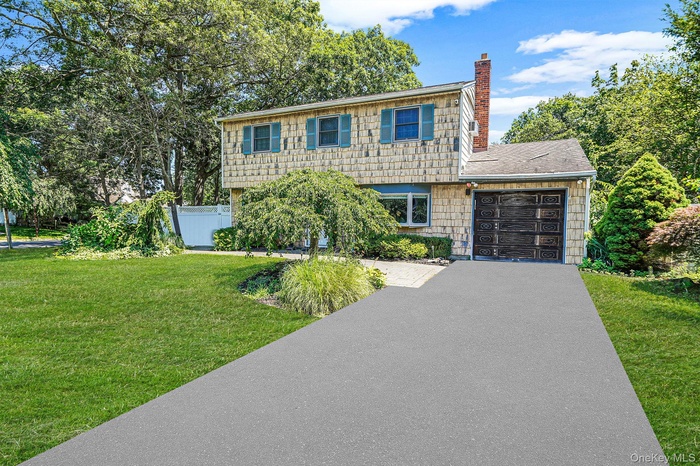 Colonial home featuring a chimney, asphalt driveway, a garage, and roof with shingles