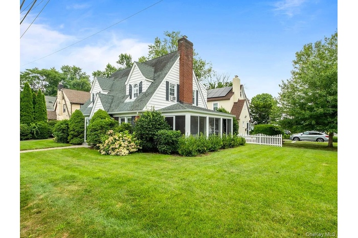 View of home's exterior with a chimney, a sunroom, solar panels, and a shingled roof